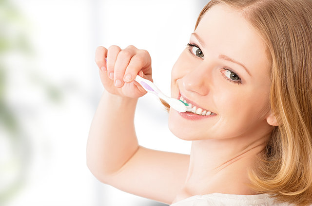 happy woman brushing her teeth with a toothbrush